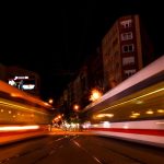 Twin trains speed past each other at night in a vibrant urban setting, creating a dynamic city atmosphere.